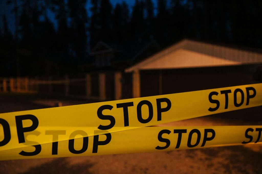 Yellow stop tape blocking a residential street at night, creating a restricted area.
