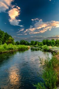 Peaceful river landscape with lush greenery and a vibrant sunset sky in Taylorsville, Utah.