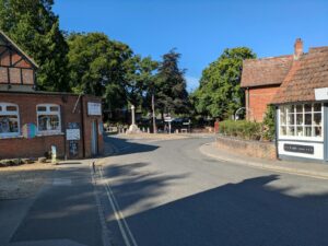 Quaint village street with historic brick buildings, trees, and sunny weather.