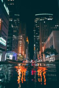 Dynamic view of illuminated skyscrapers in Houston at night reflected on wet streets.