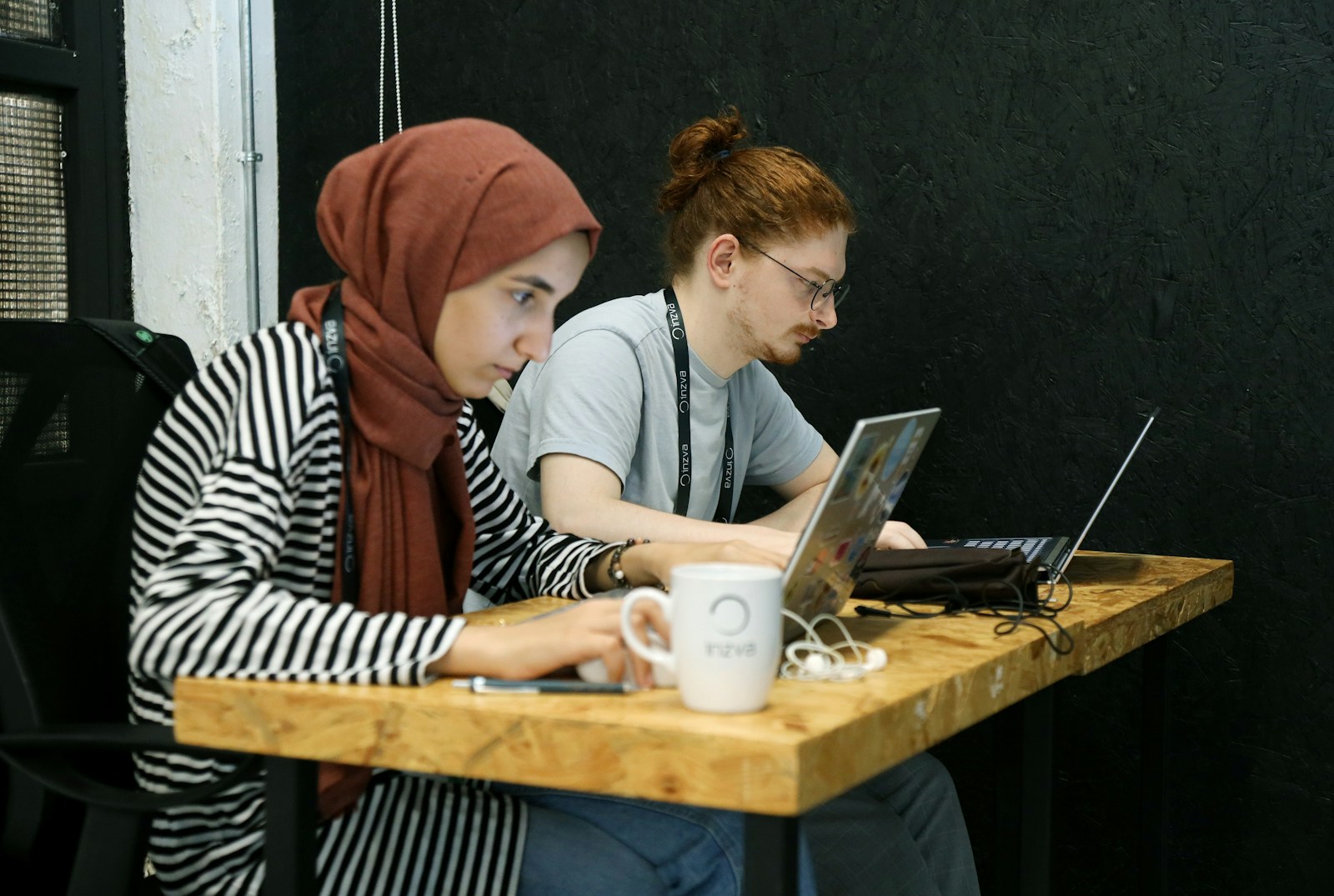 two women sitting at a table with laptops