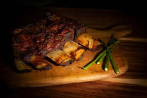 a piece of meat with a green stem on a wooden surface