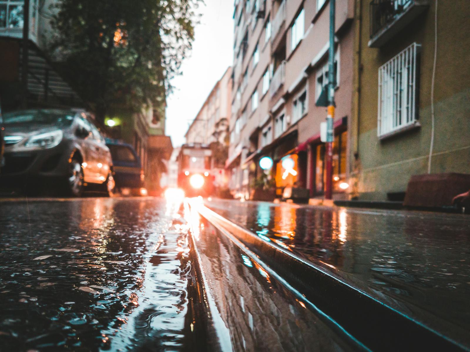 Moody street scene in Istanbul with a tram reflecting in rain-soaked pavement.