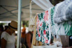 Vibrant and diverse textiles on display at an outdoor market with blurred shoppers.