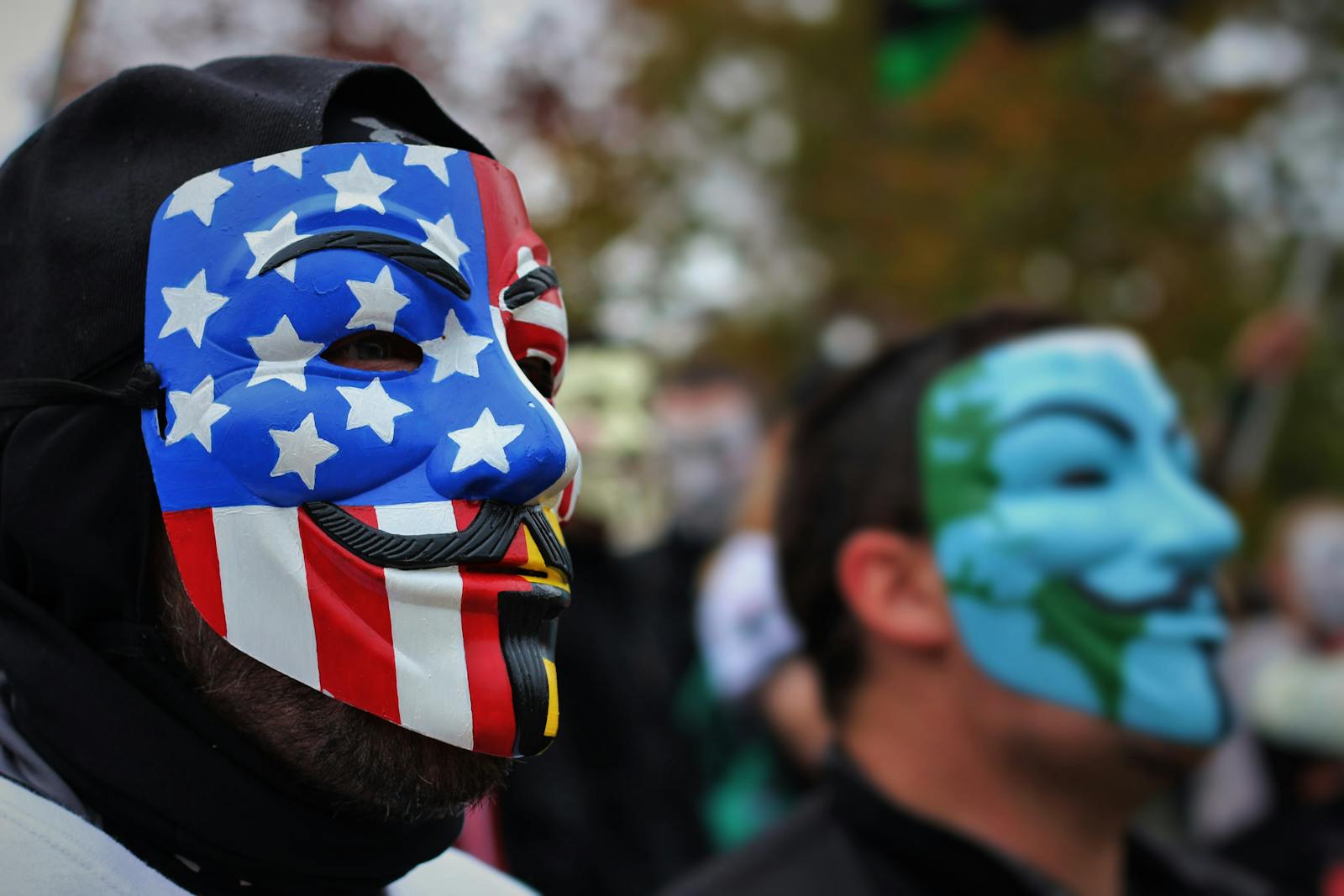 Close-up of protesters wearing Guy Fawkes masks with political themes, highlighting activism.