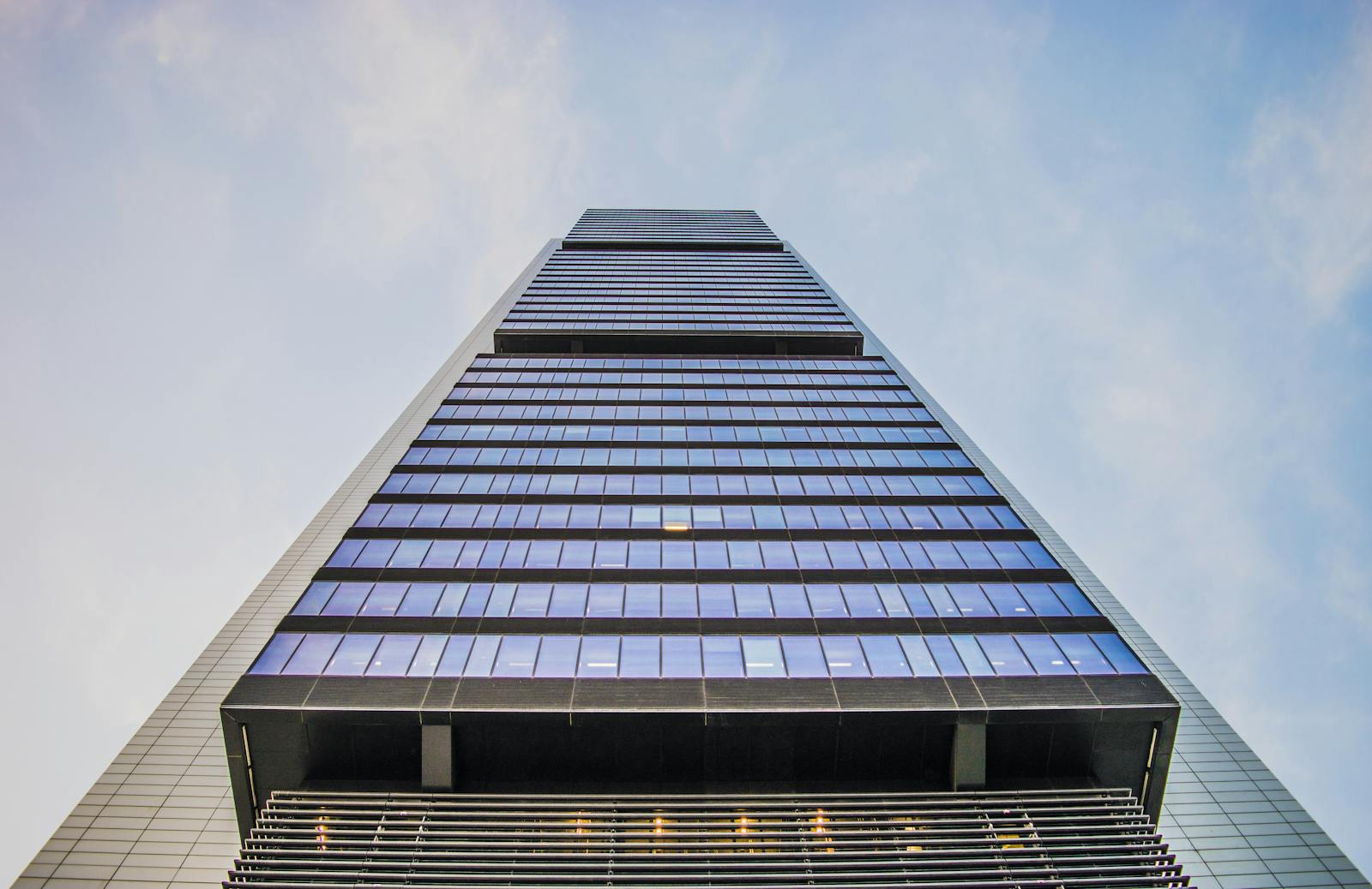 Stunning low angle view of a modern skyscraper with glass windows against a clear sky, highlighting architectural innovation.