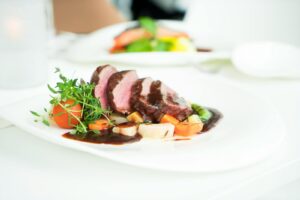 Elegant presentation of sliced beef with herbs and sauce, capturing fine dining ambiance.