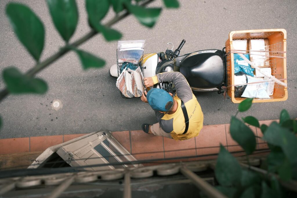 Courier on motorcycle making deliveries in Hong Kong, captured from above. Urban logistics and transport concept.