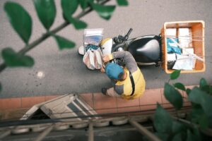 Courier on motorcycle making deliveries in Hong Kong, captured from above. Urban logistics and transport concept.