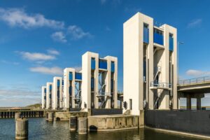 A contemporary water control structure featuring multiple pillars against a clear blue sky.