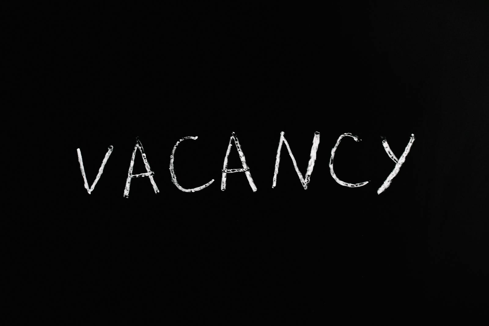 Handwritten chalk text displaying 'vacancy' on a black background.