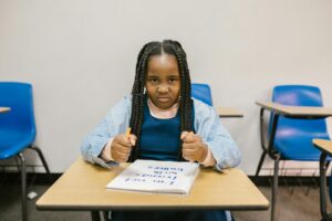 A young girl sits at a desk with a determined expression, promoting anti-bullying.