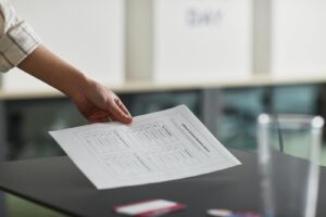 Close-up of a hand holding a ballot paper indoors, symbolizing democracy and civil rights.