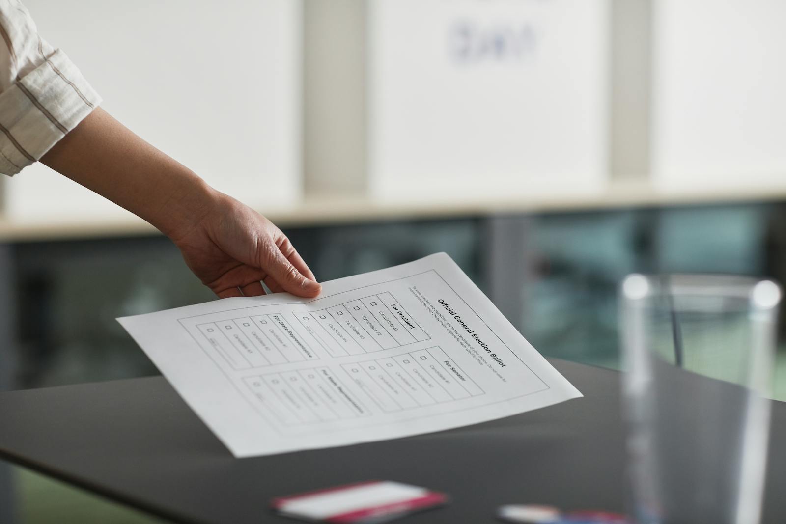 Close-up of a hand holding a ballot paper indoors, symbolizing democracy and civil rights.