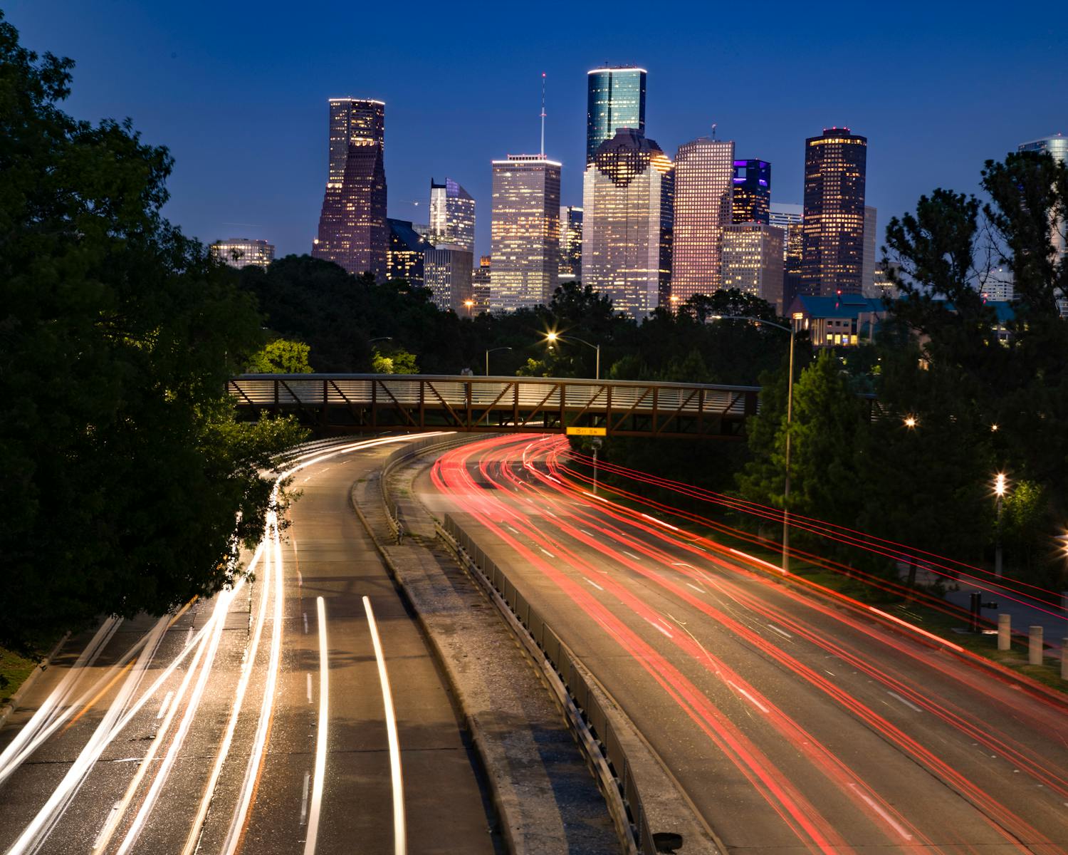 Long exposure shot of Houston's skyline at night with vibrant light trails leading into the city.
