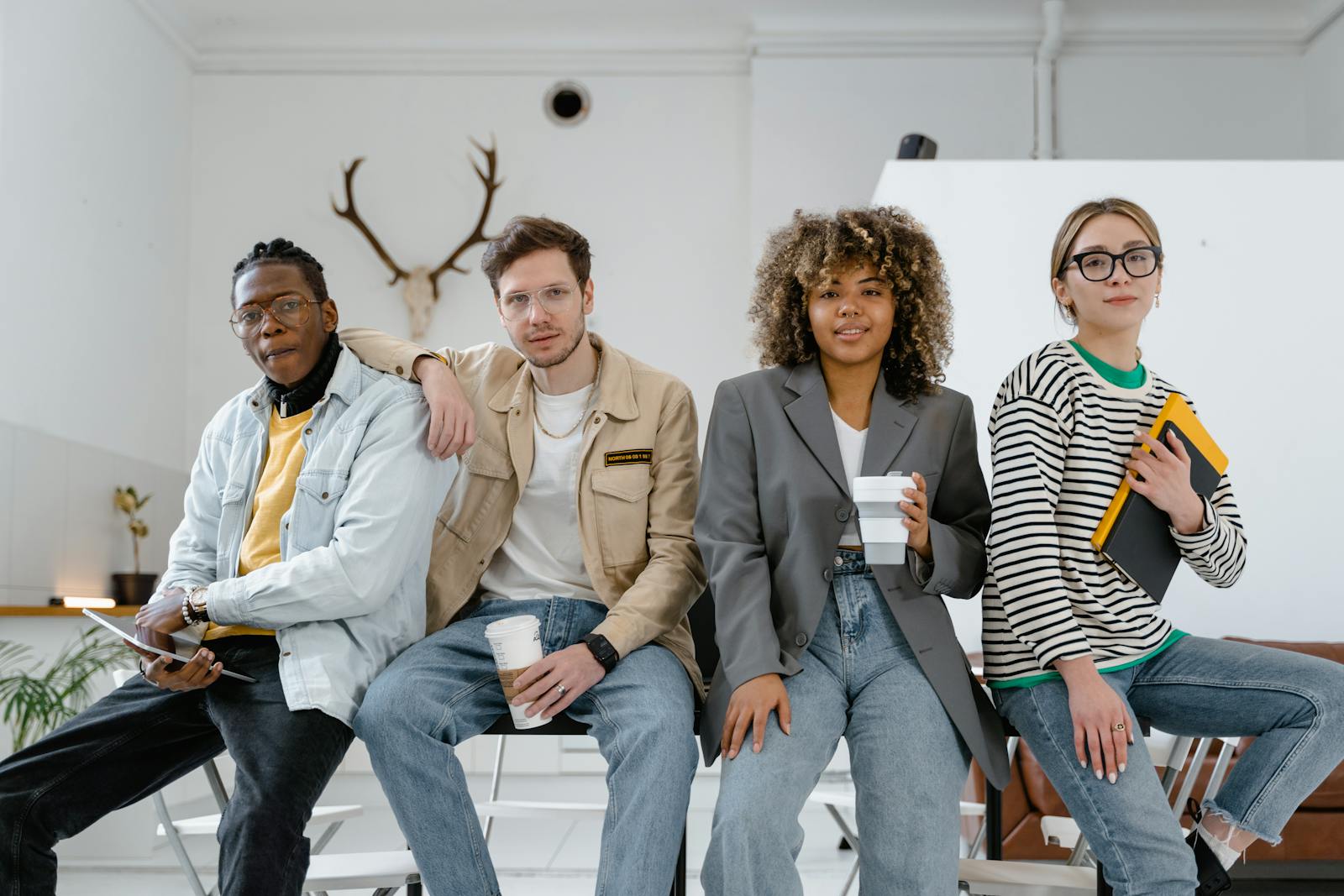 A diverse group of young professionals casually posing inside a modern office setting.