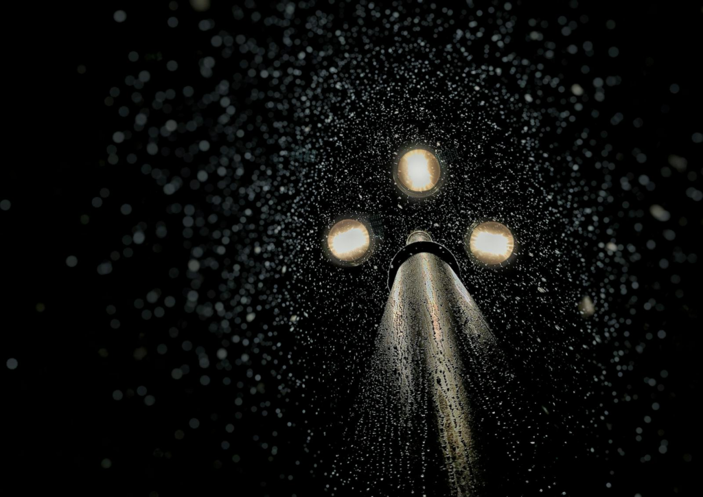 Artistic capture of rain-drenched street lamp illuminating droplets at night in Moscow.
