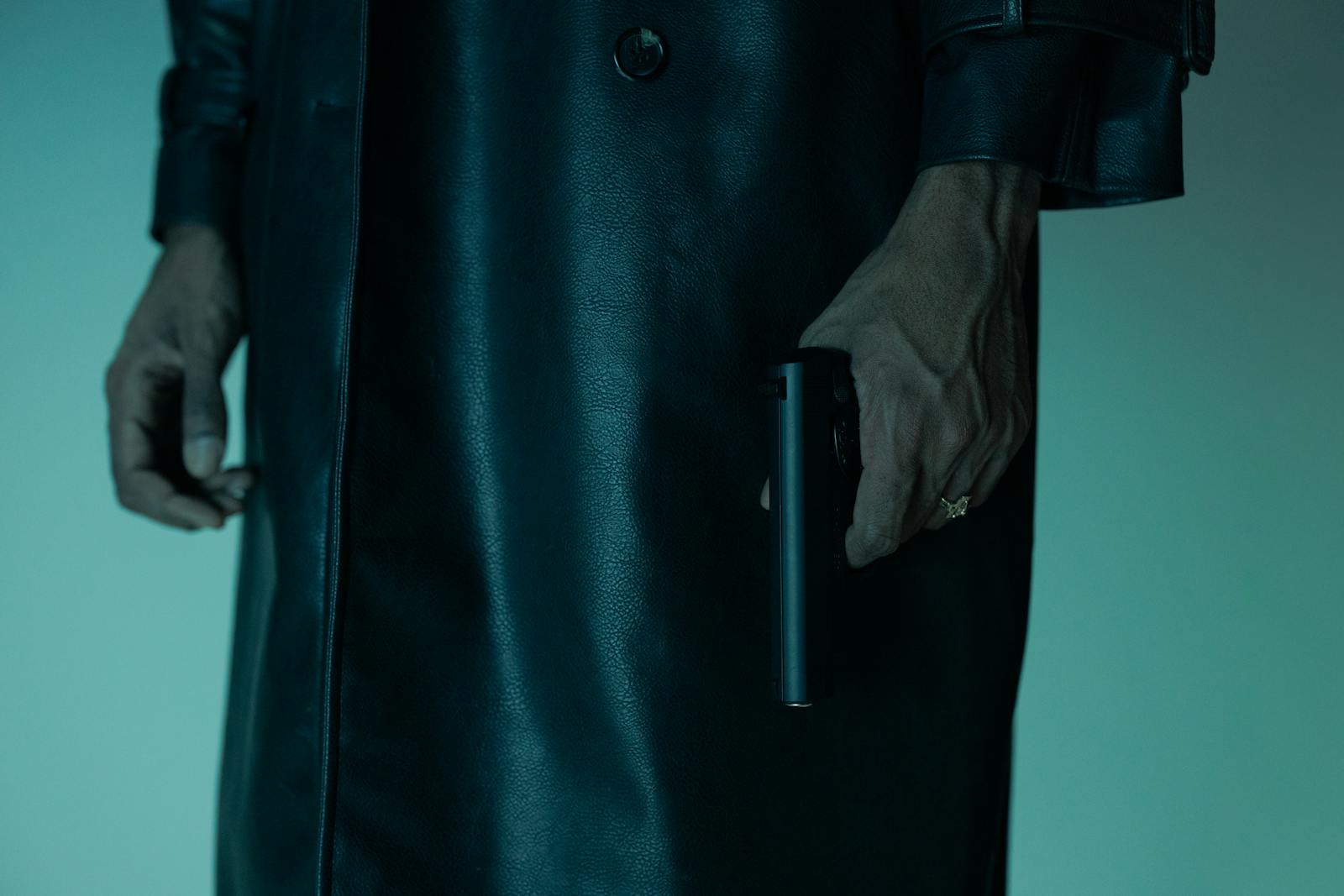 Close-up of an unrecognizable person holding a pistol, creating a mysterious and suspenseful mood.