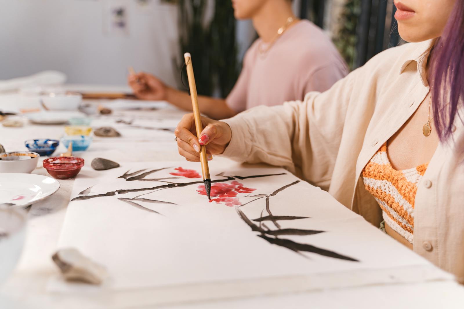 Close-up of a woman painting with a brush in an art class, focusing on creativity and technique.