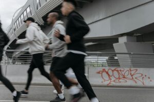 A group of people jogging briskly under an urban highway bridge showcasing graffiti and modern architecture.