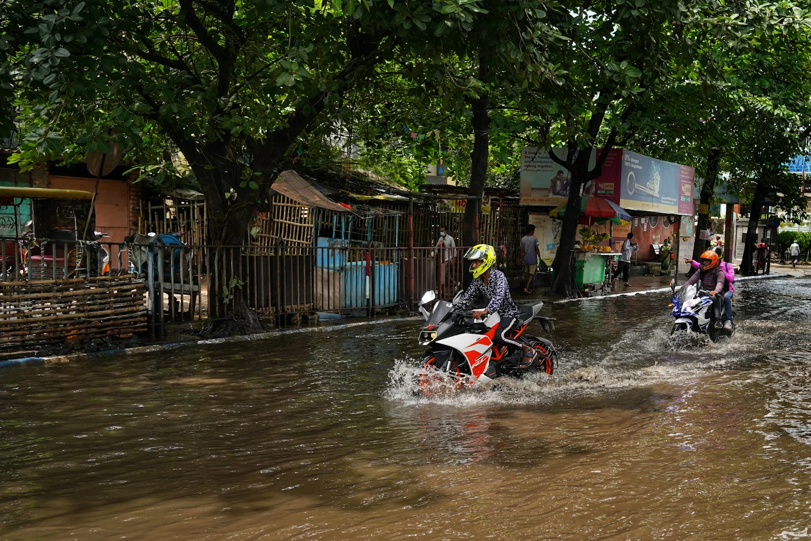 a group of people riding motorcycles through a flooded street